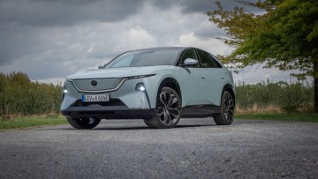 Mazda CX-6e schräg von vorn vor Wald fotografiert