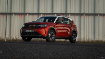 Stehend vor einer Wand von vorn fotografierter Opel Frontera in Kanyon Orange lackiert 