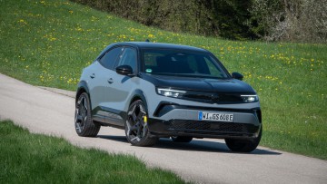 Opel Mokka GSE steht auf einem einsamen Teerstreifen und wurde von vorn fotografiert.