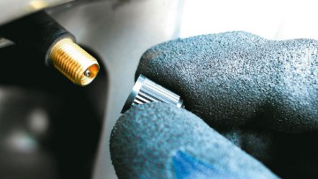 Ein Kfz-Mechaniker schraubt eine Ventilkappe auf das Ventil eines Autoreifens