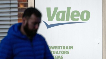 Ein Mann läuft mit gesenktem Kopf vor einem Schild mit dem Logo des Automobilzulieferers Valeo vorbei. (zu dpa: «Valeo baut weitere Stellen ab») 
