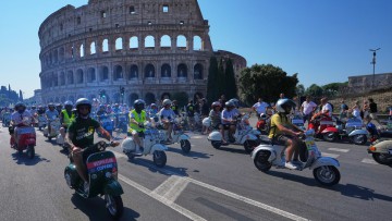Italien, Rom: Vespa-Fans fahren anlässlich der Feierlichkeiten zum 80-jährigen Jubiläum des Vespa-Rollers am Samstag, dem 27. Juni 2026, in Rom vor dem Kolosseum vorbei. Foto: Alessandra Tarantino/AP/dpa +++ dpa-Bildfunk