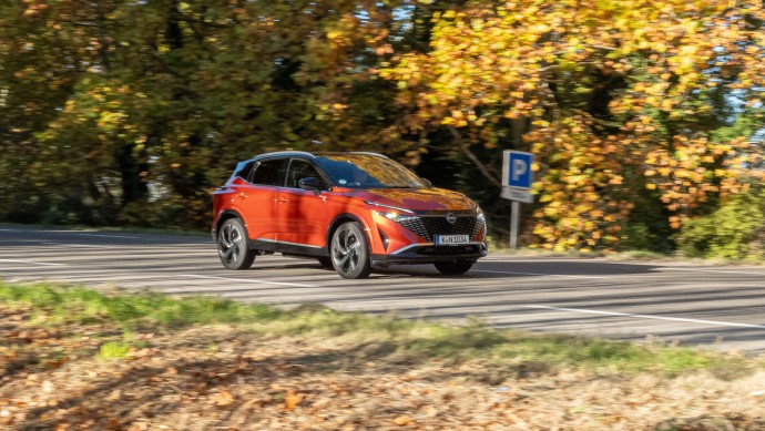 Nissan Qashqai fahrend vor Herbstbäumen