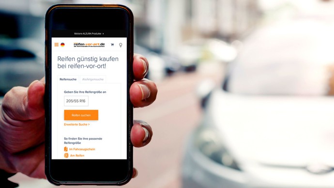 Hand hält Smartphone mit geöffneter Reifen-vor-Ort Webseite