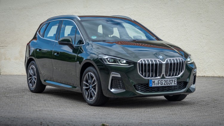 Dunkelgrüner BMW 230e steht vor gelber Hauswand und ist von schräg vorn, leicht von oben fotografiert