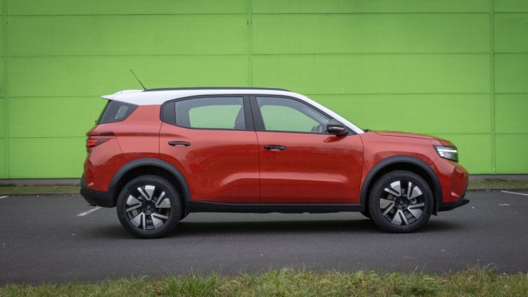 Orangefarbener Opel Frontera seitlich vor grüner Wand fotografiert