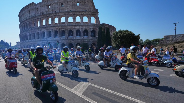 Italien, Rom: Vespa-Fans fahren anlässlich der Feierlichkeiten zum 80-jährigen Jubiläum des Vespa-Rollers am Samstag, dem 27. Juni 2026, in Rom vor dem Kolosseum vorbei. Foto: Alessandra Tarantino/AP/dpa +++ dpa-Bildfunk
