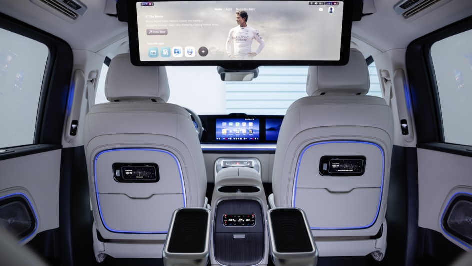 Foto von hinten auf die Rückseite der Vordersitze im Mercedes VLE mit ausgefahrenem Mega-Bildschirm, der aus der Dachverkleidung elektrisch angetrieben, herausfährt.