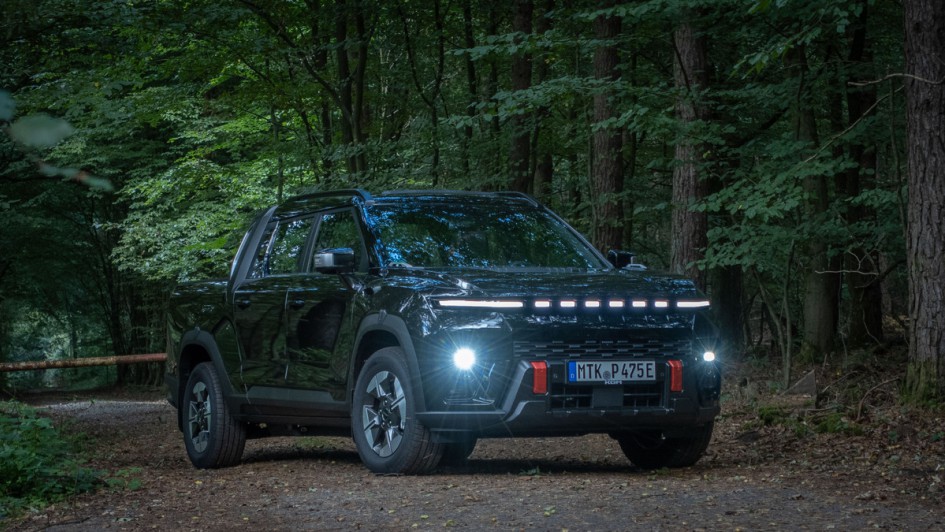 Schwarzer KGM Musso EV von schräg vorn fotografiert und mit eingeschaltetem Abblendlicht fotografiert