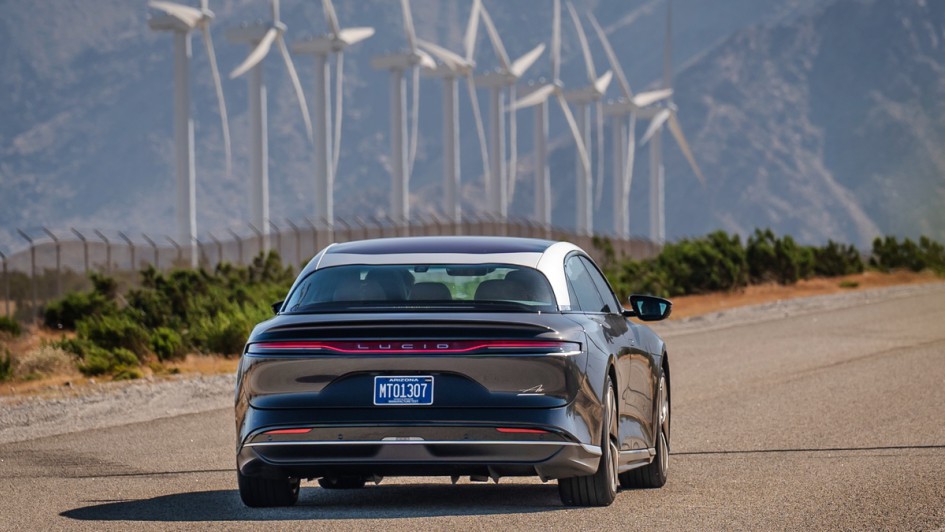 Lucid Air Touring fahrend von hinten in den USA fotografiert, Windräder stehen im Hintergrund