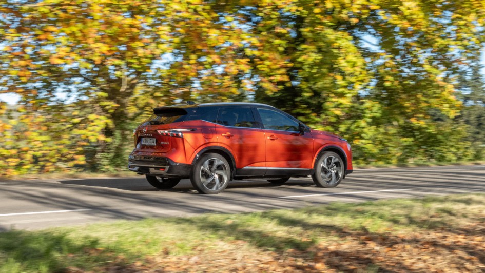 Nissan Qashqai fahrend von schräg hinten vor leuchtendem Herbstwald