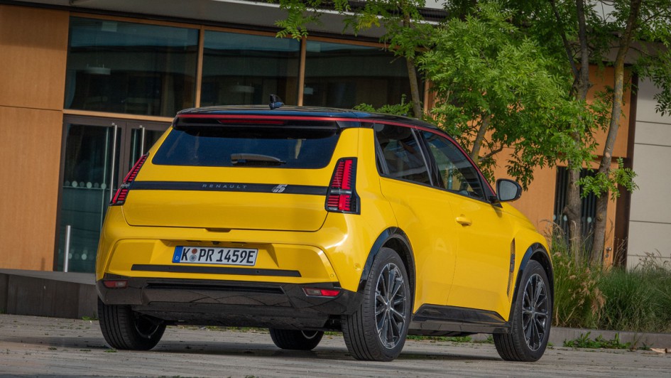 Gelber Renault 5 von hinten stehend fotografiert vor modernem Schulgebäude
