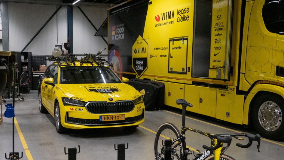 Skoda Superb mit Team-Beklebung des Profi-Radsportteams Visma Lease a bike in Garage neben Lkw parkend