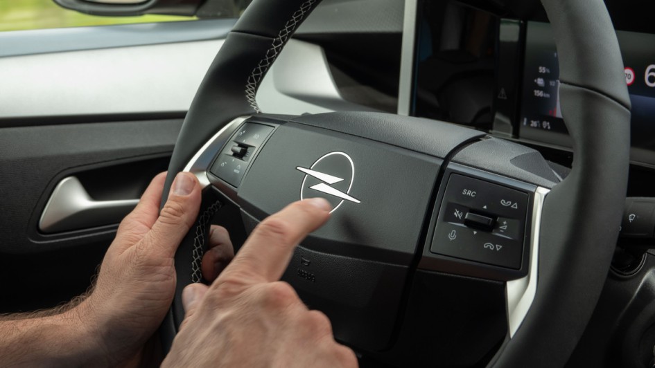 Finger tippt auf das Opel-Logo im Pralltopf des Frontera-Lenkrads