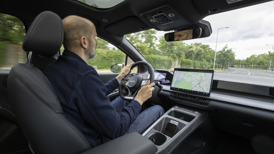 Fahrer sitzt im BYD Dolphin G und fährt durch Berlin, Aufnahme von hinten rechts gemacht