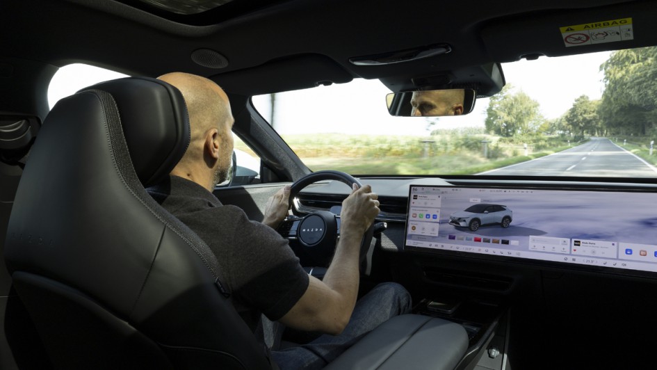 Mazda CX-6e fahrend, Foto von der Rückbank auf den Fahrer