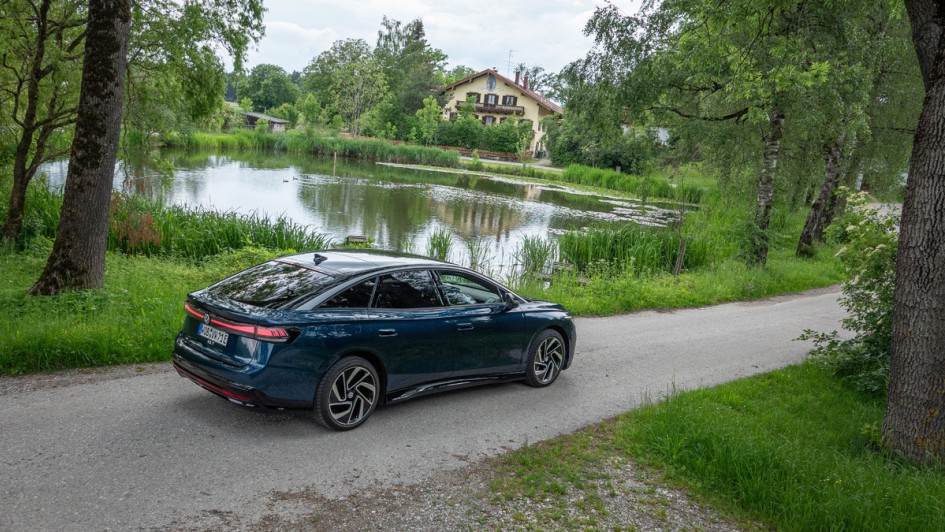 VW ID.7 Pro vor Teich mit bayerischem Wohnhaus im Hintergrund